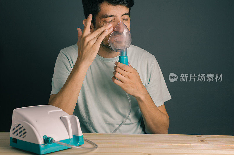 有鼻窦炎症状的男子使用家用吸入器/喷雾器画像